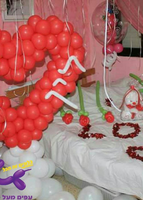 בלון לב ענק עם פיזור בלונים על המיטה